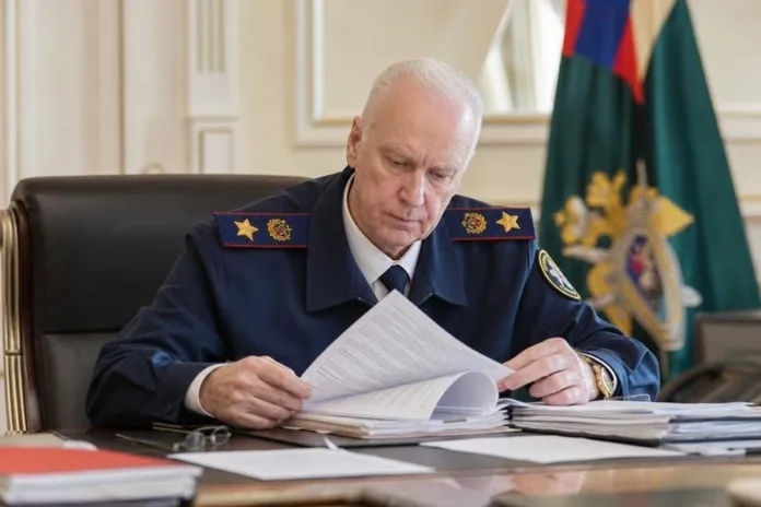 Мужчина в форменной одежде сидит за столом и изучает документы в кабинете; на заднем плане виден флаг.