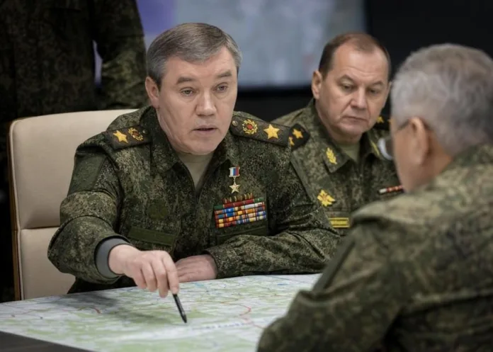 Военные в форме обсуждают карту за столом; один из них указывает на участок карты ручкой.