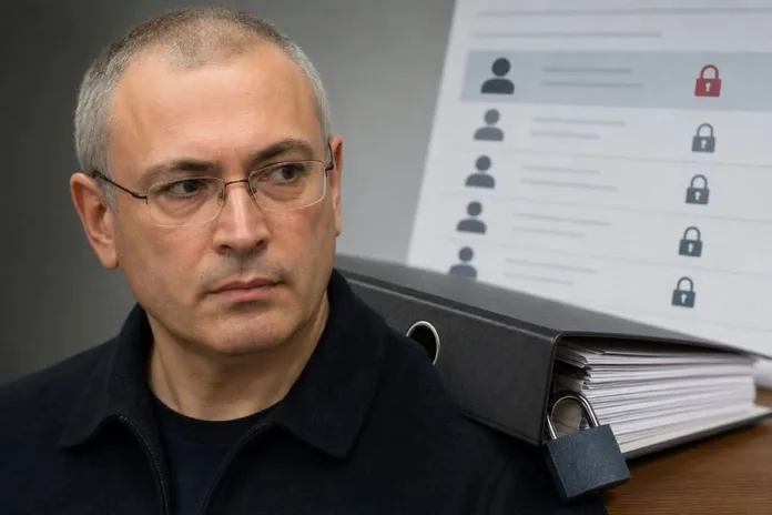 Мужчина в очках сидит перед папкой с документами и изображением списка с замками на экране.