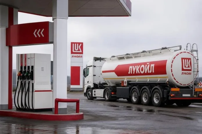 Автоцистерна с логотипом «Лукойл» стоит у топливной колонки на заправочной станции.
