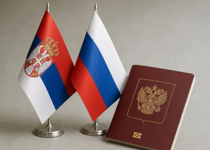 На столе рядом стоят флаги Сербии и России, справа лежит бордовый паспорт с золотым гербом.
